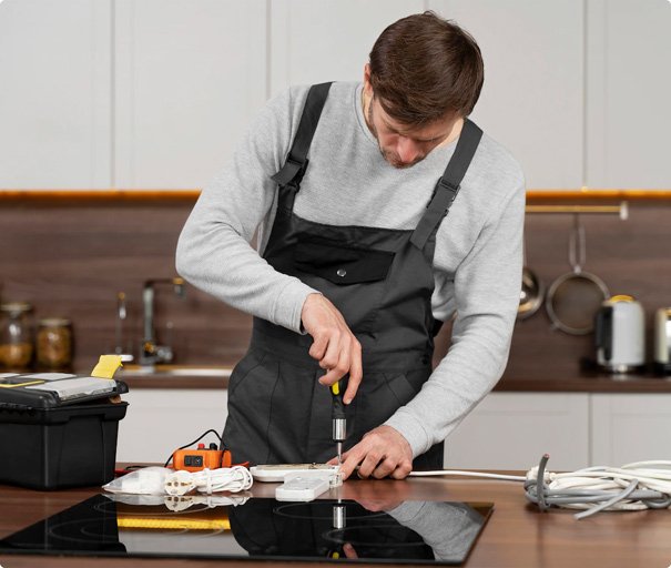 Electrician repairing an electrical socket with a screwdriver on a kitchen counter.
