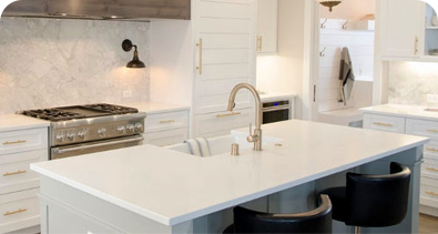 Modern white kitchen with island sink, marble backsplash, and stainless steel appliances