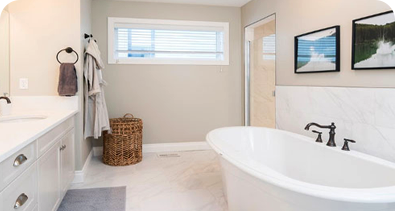 Modern bathroom with freestanding bathtub, white cabinets, and minimalist decor.